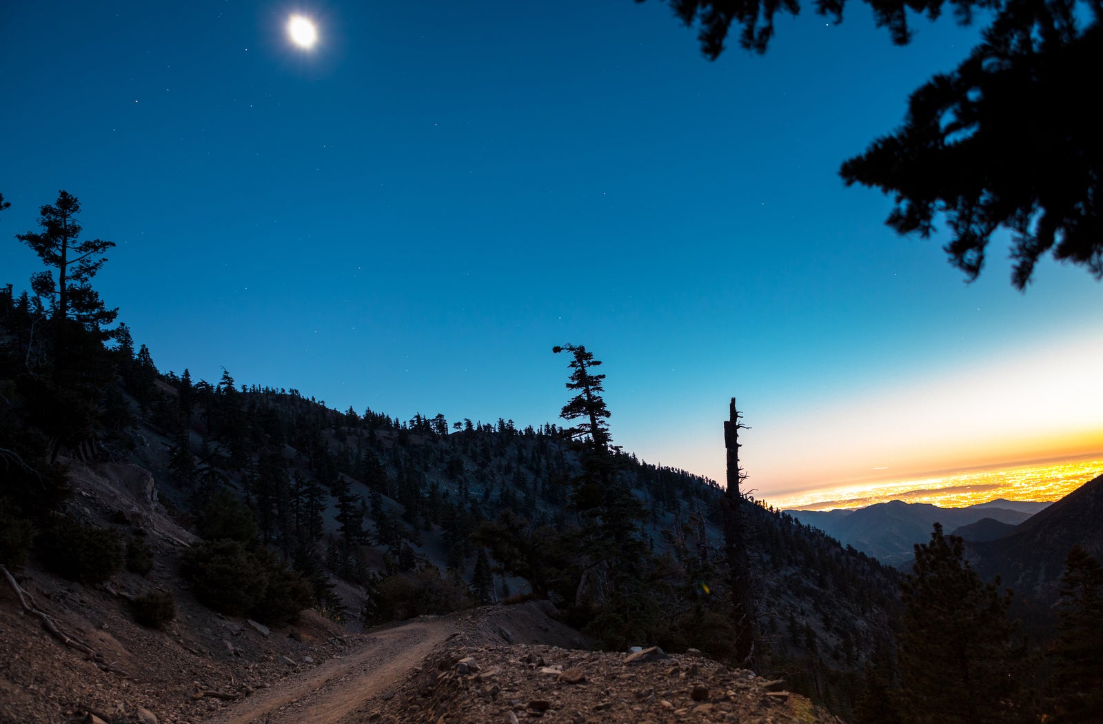 Hikers walking under the moon at dusk on Mt Baldy