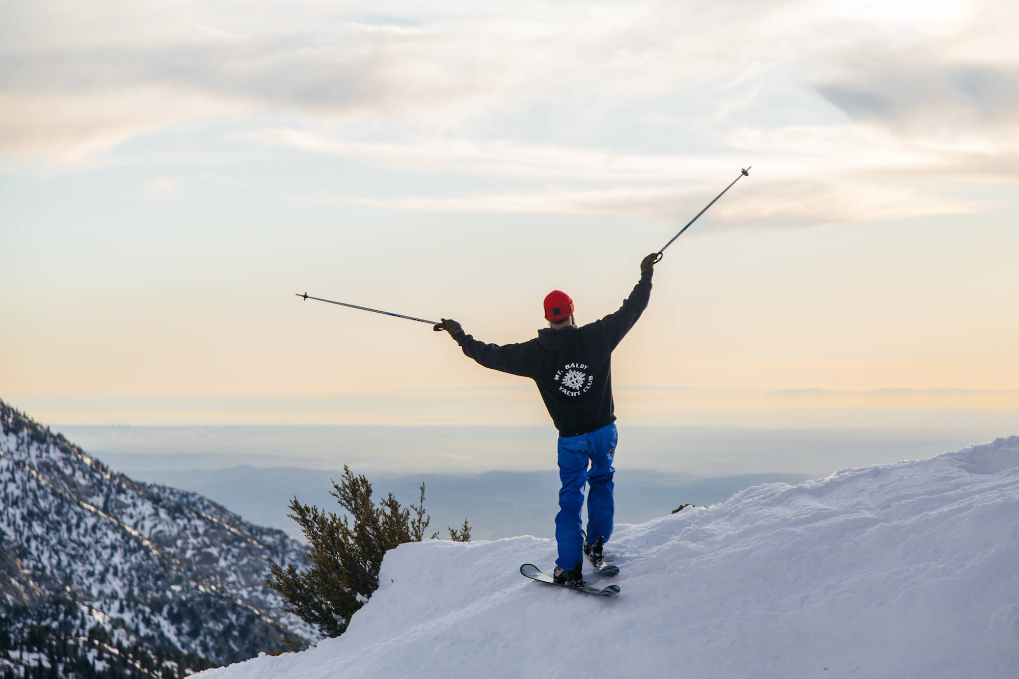 A snowboarder celebrating above the clouds on Mt Baldy